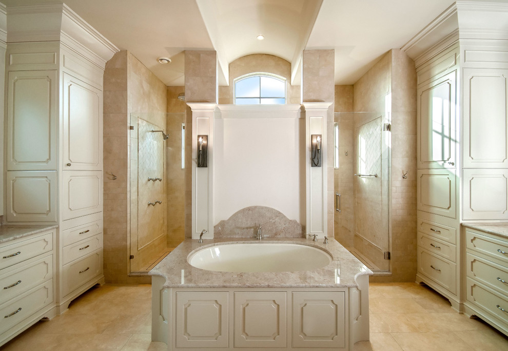 Inredning av ett klassiskt mycket stort en-suite badrum, med ett nedsänkt handfat, luckor med upphöjd panel, vita skåp, granitbänkskiva, ett undermonterat badkar, en dubbeldusch, beige kakel, stenkakel, vita väggar och travertin golv