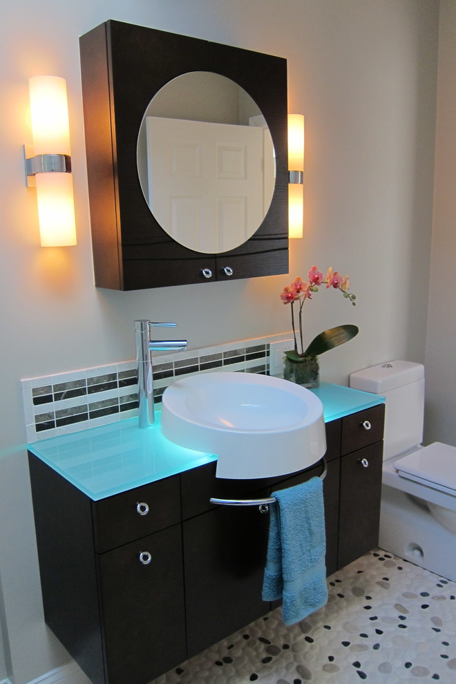 Modelo de cuarto de baño contemporáneo con lavabo sobreencimera, armarios con paneles lisos, sanitario de una pieza, paredes blancas y encimera de vidrio