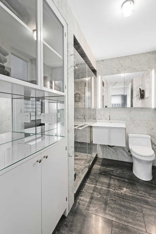 Immagine di una piccola stanza da bagno padronale minimalista con ante lisce, ante bianche, doccia alcova, WC monopezzo, pistrelle in bianco e nero, piastrelle in pietra, pareti bianche, pavimento in marmo e lavabo sospeso