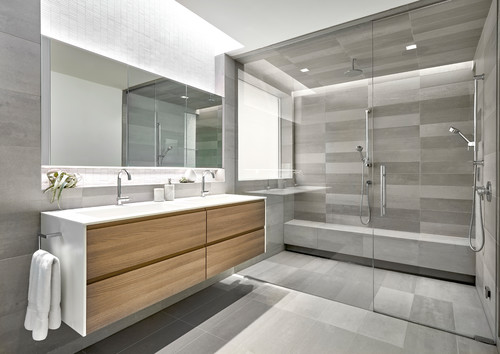 Modern bathroom with floating double-sink vanity, light oak slab-front bathroom cabinets, white quartz top, and large glass walk-in shower.