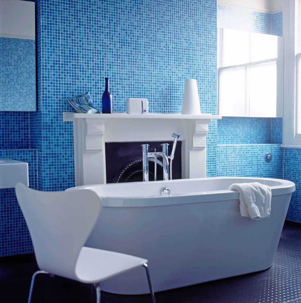 На фото: детская ванная комната среднего размера в современном стиле с плоскими фасадами, отдельно стоящей ванной, открытым душем, инсталляцией, синей плиткой, стеклянной плиткой, синими стенами, полом из винила, подвесной раковиной и столешницей из плитки с