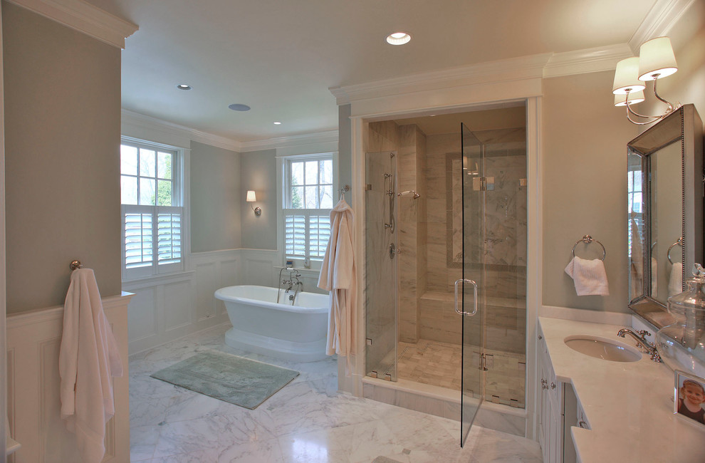 Пример оригинального дизайна: большая главная ванная комната в классическом стиле с врезной раковиной, фасадами с утопленной филенкой, белыми фасадами, столешницей из гранита, отдельно стоящей ванной, угловым душем, унитазом-моноблоком, белой плиткой, плиткой из листового камня, зелеными стенами, мраморным полом, серым полом, душем с распашными дверями и бежевой столешницей