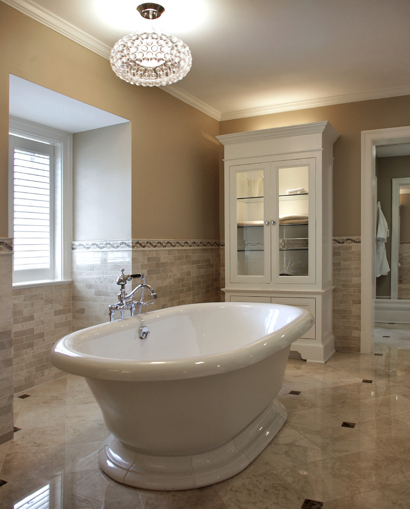 Immagine di un'ampia stanza da bagno padronale american style con ante con riquadro incassato, ante bianche, vasca freestanding, doccia alcova, piastrelle beige, piastrelle in pietra, pareti beige e pavimento in marmo