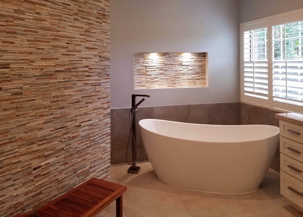 Inspiration for a medium sized traditional ensuite wet room bathroom in Miami with shaker cabinets, white cabinets, a freestanding bath, a one-piece toilet, multi-coloured tiles, stone tiles, multi-coloured walls, porcelain flooring, a submerged sink, marble worktops, beige floors and an open shower.