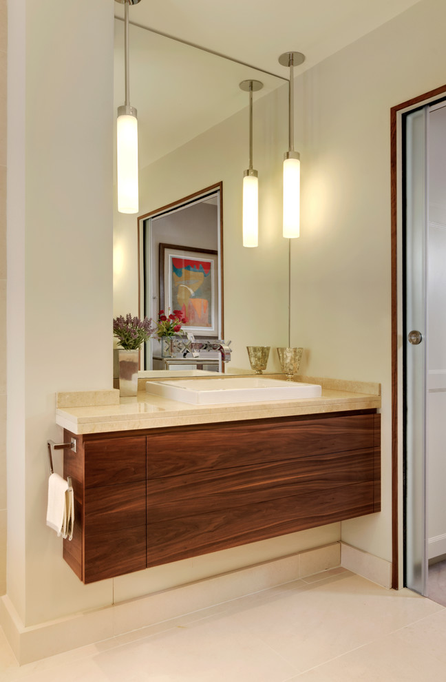 Contemporary bathroom in London with a built-in sink, medium wood cabinets, marble worktops, a freestanding bath, a walk-in shower, a wall mounted toilet, beige tiles and limestone flooring.