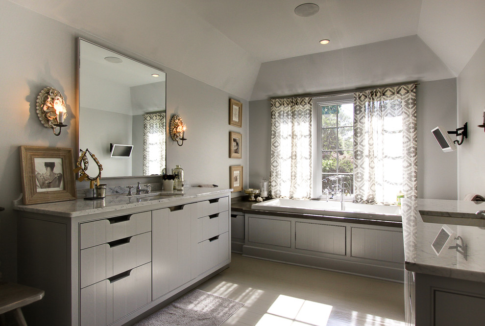 Cette photo montre une salle de bain tendance en bois brun avec un placard à porte affleurante, un plan de toilette en marbre, une baignoire posée et parquet peint.