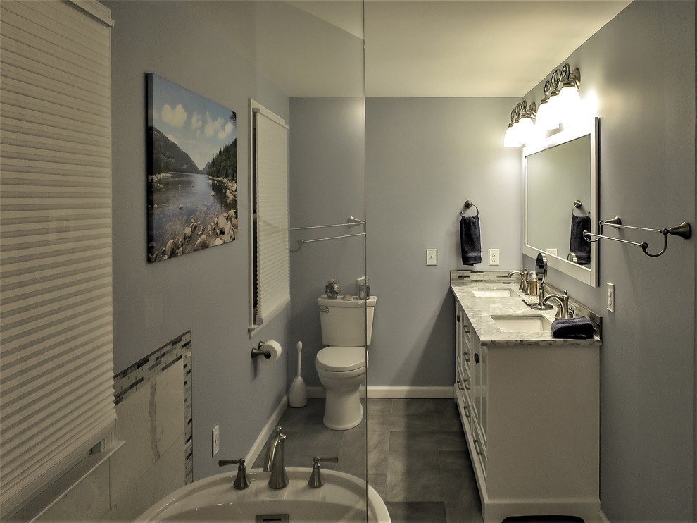 На фото: большая главная ванная комната в стиле неоклассика (современная классика) с фасадами в стиле шейкер, белыми фасадами, отдельно стоящей ванной, душем без бортиков, раздельным унитазом, белой плиткой, керамогранитной плиткой, синими стенами, полом из керамогранита, врезной раковиной, мраморной столешницей, серым полом, душем с распашными дверями и серой столешницей с