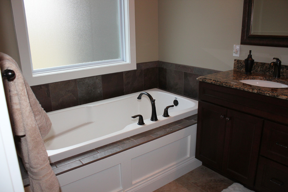Exempel på ett amerikanskt badrum, med släta luckor, skåp i mörkt trä, ett platsbyggt badkar, brun kakel, porslinskakel, beige väggar, klinkergolv i porslin och granitbänkskiva