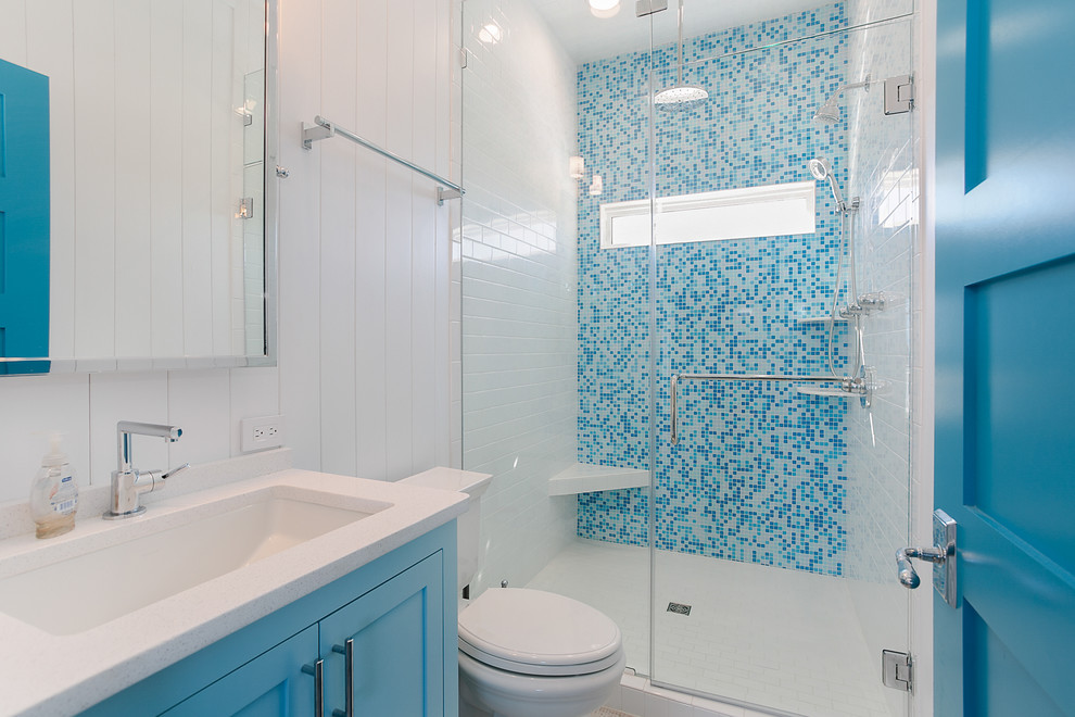 Aménagement d'une petite douche en alcôve principale bord de mer avec un placard à porte shaker, des portes de placard bleues, un carrelage bleu, mosaïque, un mur blanc, un lavabo encastré, un sol blanc et un plan de toilette blanc.