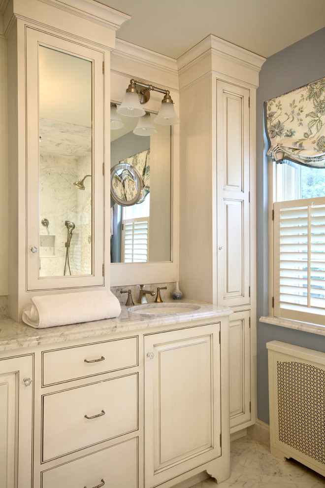 Modelo de cuarto de baño clásico con lavabo bajoencimera, puertas de armario blancas y armarios con paneles con relieve