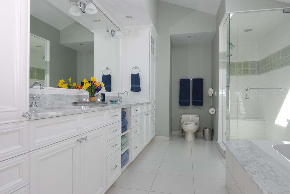 This is an example of a medium sized traditional bathroom in Chicago with recessed-panel cabinets, white cabinets, a built-in bath, an alcove shower, a one-piece toilet, white tiles, ceramic tiles, grey walls, ceramic flooring and a submerged sink.