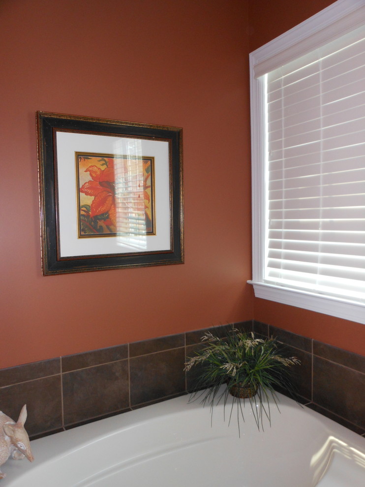 Cette image montre une salle de bain principale design de taille moyenne avec une baignoire posée, un carrelage marron, des carreaux de porcelaine et un mur rouge.