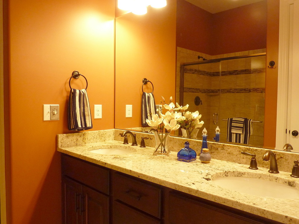 Foto på ett mellanstort funkis beige en-suite badrum, med luckor med upphöjd panel, bruna skåp, beige kakel, orange väggar, klinkergolv i keramik, ett undermonterad handfat, granitbänkskiva, beiget golv och dusch med skjutdörr