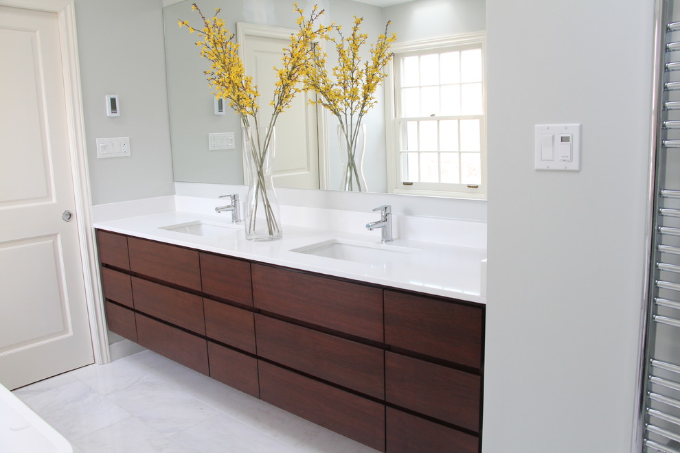 Large modern ensuite bathroom in Other with a submerged sink, flat-panel cabinets, medium wood cabinets, a freestanding bath, a built-in shower, white tiles, grey walls and marble flooring.