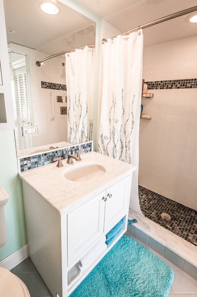 Example of a mid-sized beach style 3/4 beige tile, black and white tile, brown tile and mosaic tile alcove shower design in Miami with recessed-panel cabinets, white cabinets, a two-piece toilet, green walls, an undermount sink and granite countertops