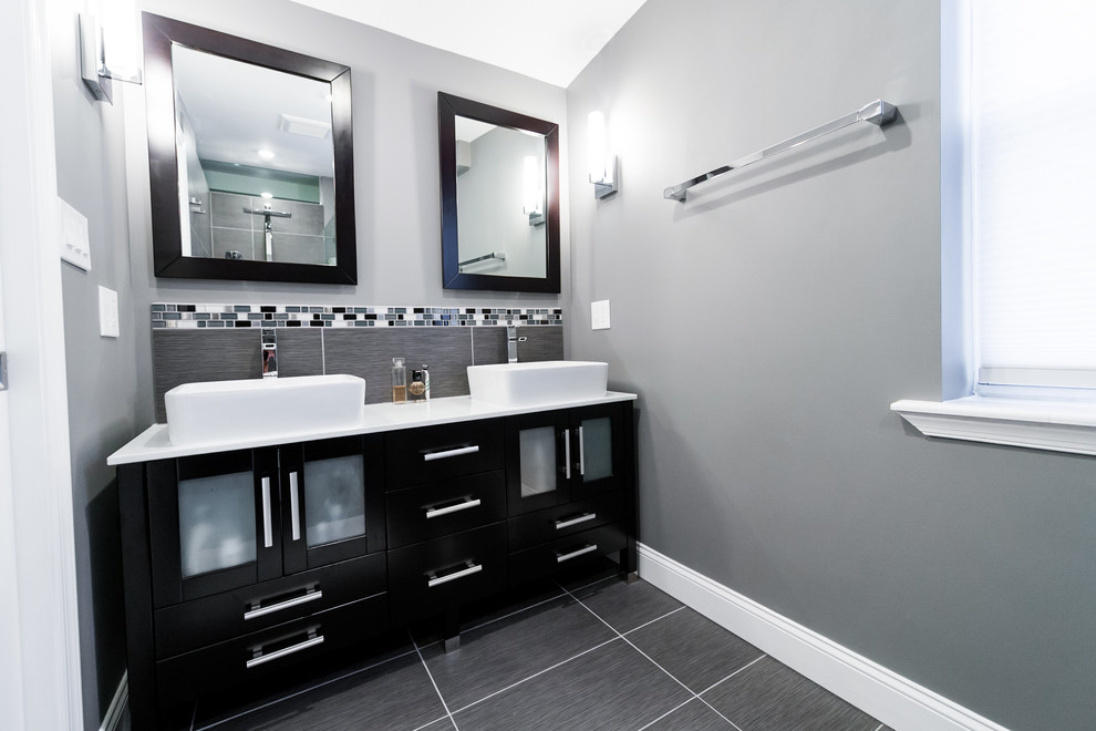 Modern inredning av ett litet en-suite badrum, med ett fristående handfat, en kantlös dusch, en toalettstol med separat cisternkåpa, grå kakel, keramikplattor, grå väggar och klinkergolv i keramik
