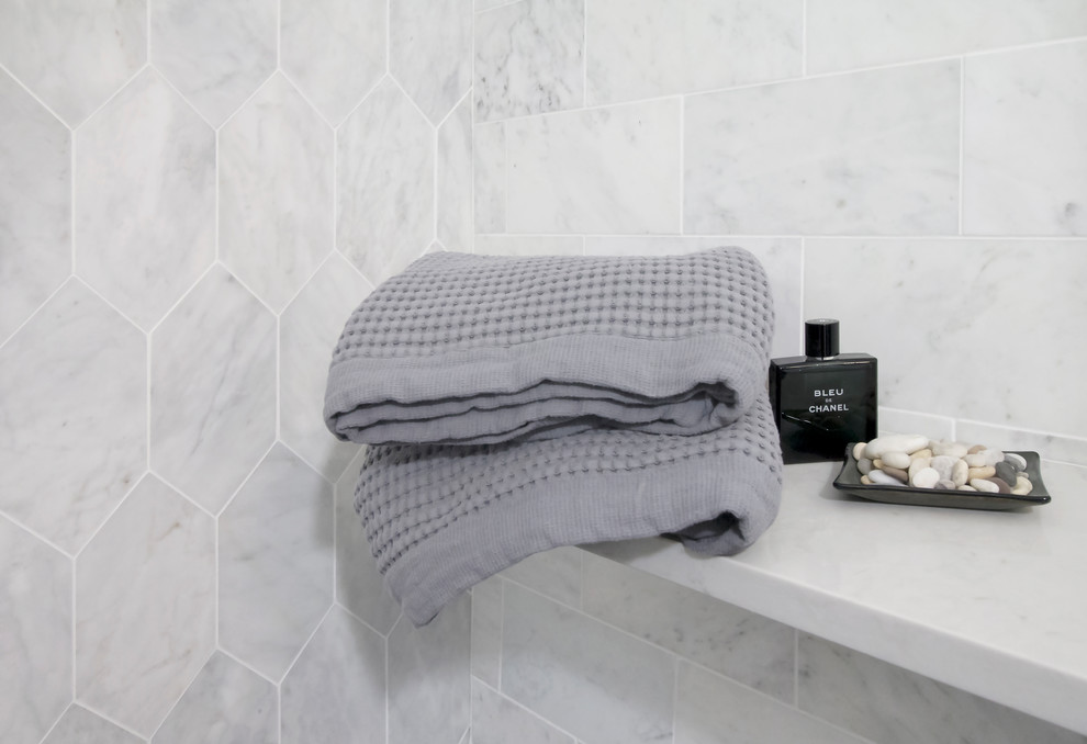 Inredning av ett 60 tals litet vit vitt en-suite badrum, med släta luckor, grå skåp, ett fristående badkar, en dusch i en alkov, en toalettstol med hel cisternkåpa, grå kakel, marmorkakel, grå väggar, klinkergolv i porslin, ett undermonterad handfat, bänkskiva i akrylsten, grått golv och dusch med gångjärnsdörr