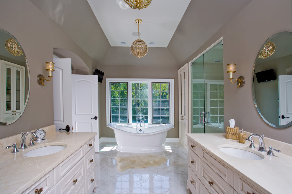 Foto på ett stort vintage en-suite badrum, med ett undermonterad handfat, beige skåp, ett fristående badkar, en dusch i en alkov, vit kakel, stenkakel, bruna väggar, marmorgolv, marmorbänkskiva och luckor med upphöjd panel