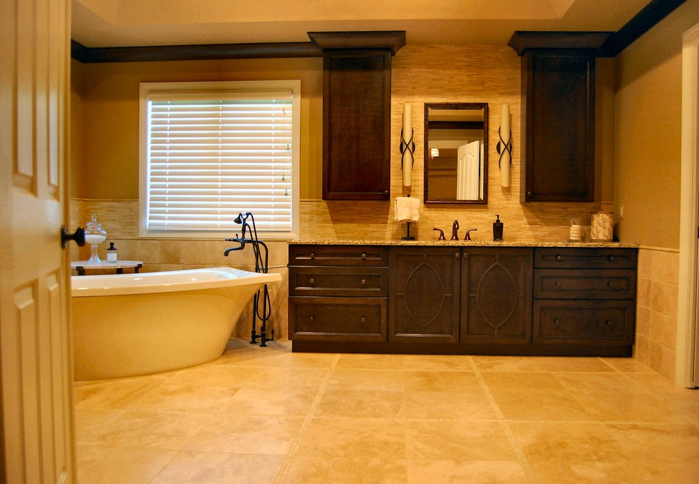 Large classic ensuite bathroom in Philadelphia with dark wood cabinets, a freestanding bath, limestone flooring, a submerged sink, granite worktops, recessed-panel cabinets, an alcove shower, beige tiles, stone tiles, beige walls and brown floors.