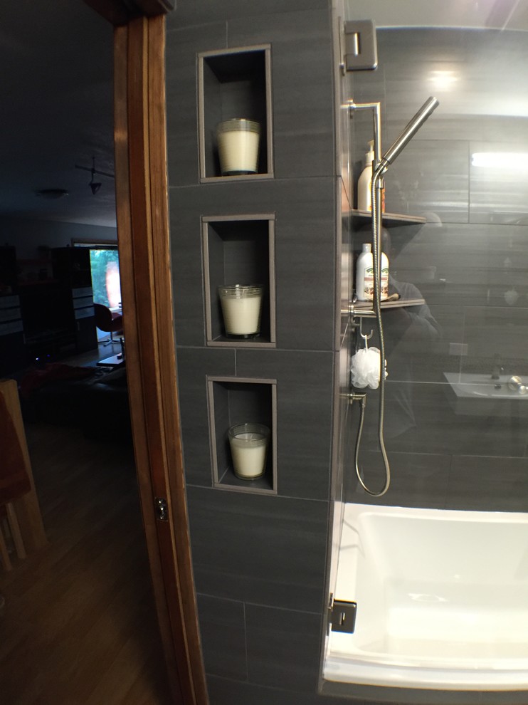 Inspiration for a medium sized contemporary ensuite bathroom in Portland with solid surface worktops, an alcove bath, a shower/bath combination, a one-piece toilet, black tiles, porcelain tiles, black walls, flat-panel cabinets and an integrated sink.
