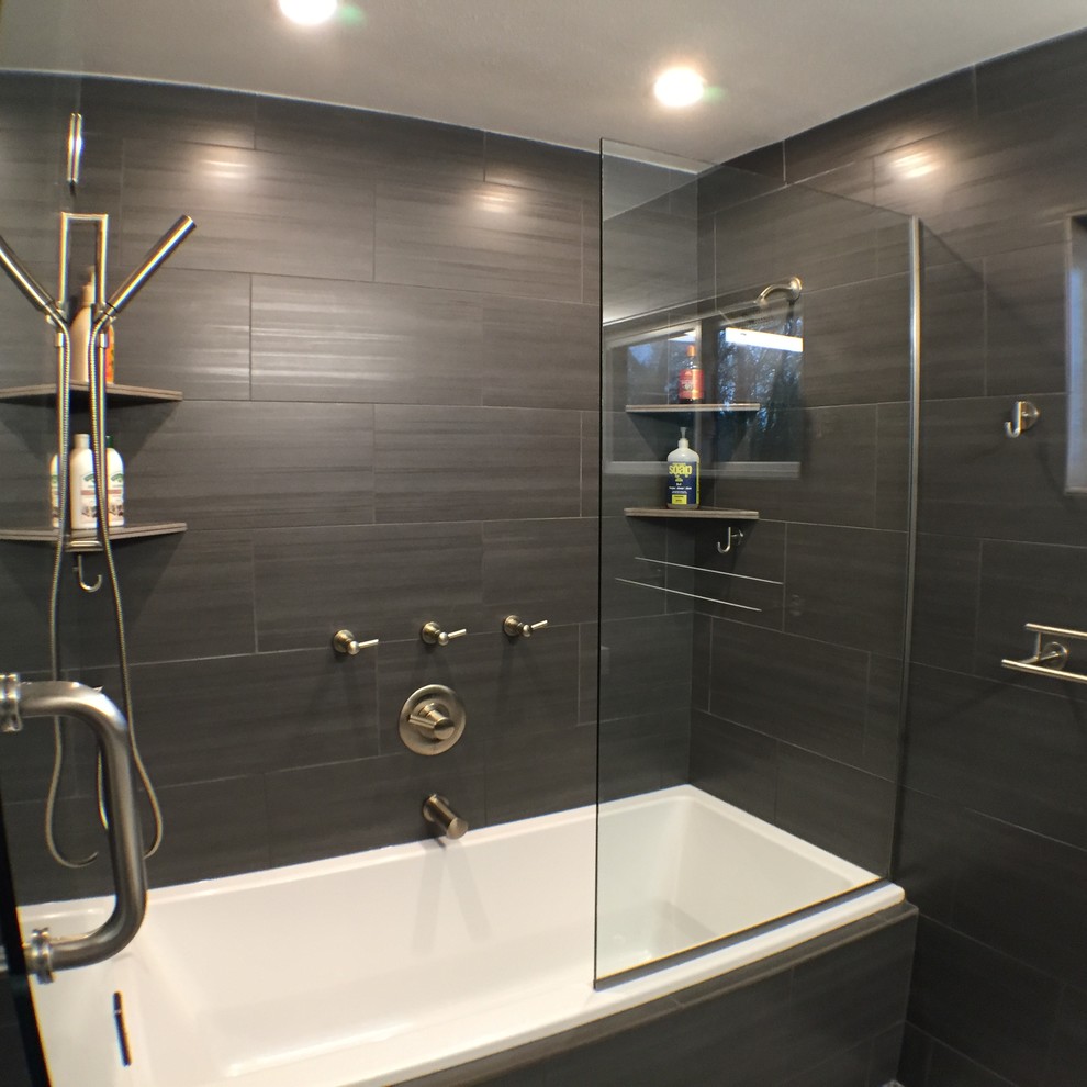 На фото: главная ванная комната среднего размера в современном стиле с столешницей из искусственного камня, ванной в нише, душем над ванной, унитазом-моноблоком, черной плиткой, керамогранитной плиткой и черными стенами