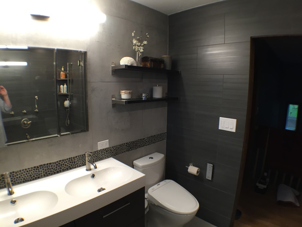 Пример оригинального дизайна: главная ванная комната среднего размера в современном стиле с столешницей из искусственного камня, ванной в нише, душем над ванной, унитазом-моноблоком, черной плиткой, керамогранитной плиткой, черными стенами, плоскими фасадами и монолитной раковиной