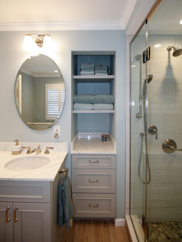 Exempel på ett stort klassiskt vit vitt en-suite badrum, med släta luckor, grå skåp, ett fristående badkar, en hörndusch, en toalettstol med separat cisternkåpa, vit kakel, porslinskakel, blå väggar, klinkergolv i porslin, ett undermonterad handfat, bänkskiva i kvarts, brunt golv och dusch med gångjärnsdörr