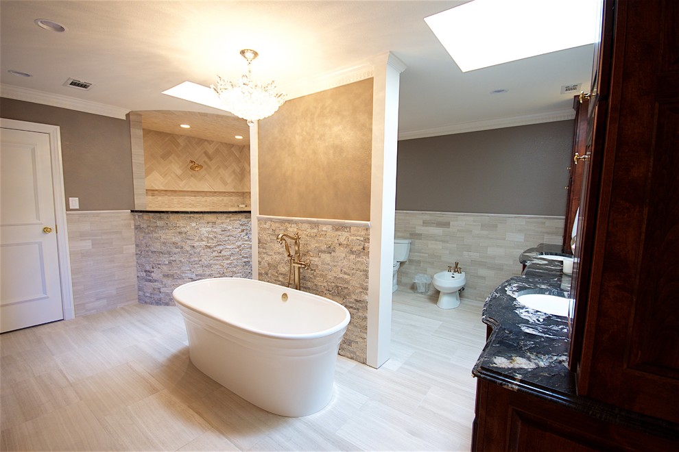 This is an example of a large contemporary ensuite bathroom in Austin with beaded cabinets, dark wood cabinets, a freestanding bath, a walk-in shower, a bidet, beige tiles, beige walls, ceramic flooring, a built-in sink and granite worktops.