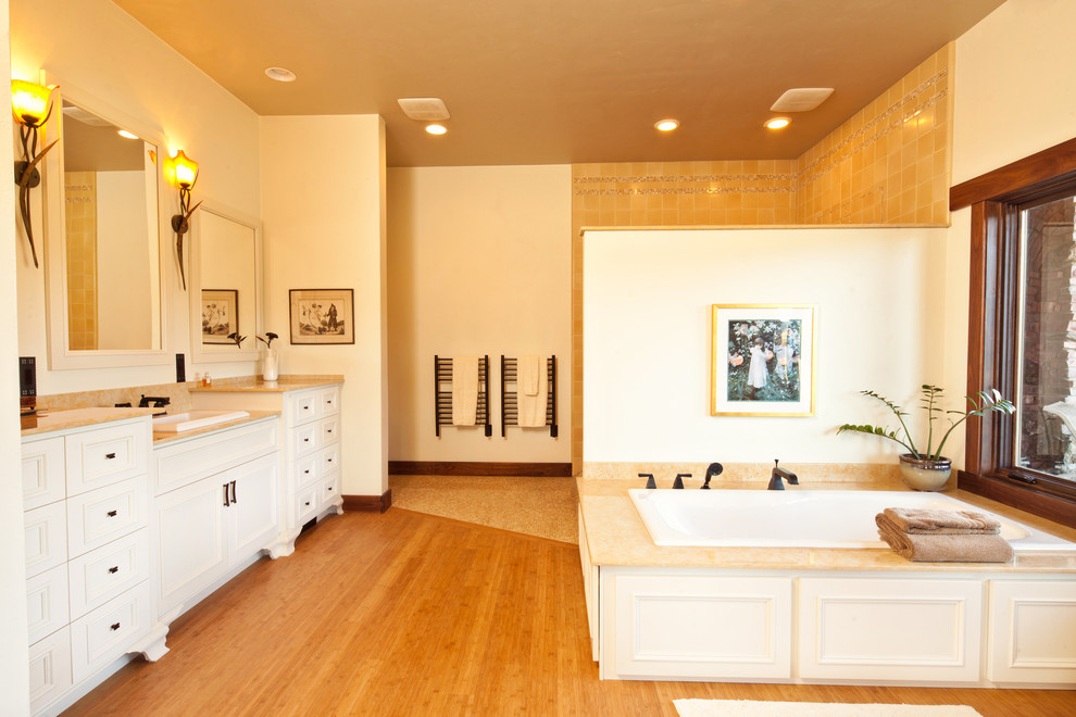 Inredning av ett klassiskt stort en-suite badrum, med luckor med profilerade fronter, vita skåp, ett platsbyggt badkar, en dusch i en alkov, beige kakel, cementkakel, beige väggar, ljust trägolv, ett nedsänkt handfat, bänkskiva i kalksten, beiget golv och med dusch som är öppen