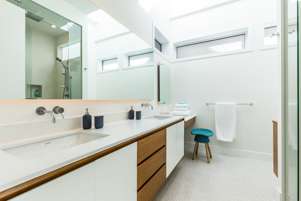 Cette photo montre une salle de bain tendance avec un placard à porte plane, des portes de placard blanches, un plan de toilette en quartz modifié, un mur blanc et un lavabo encastré.