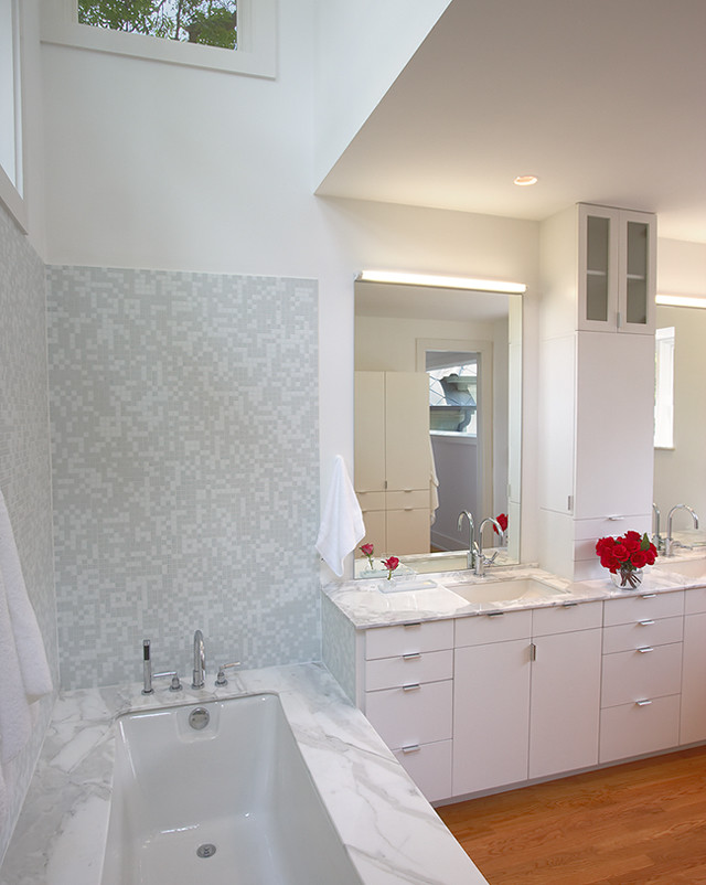 Ispirazione per una grande stanza da bagno padronale minimal con pareti bianche, pavimento in legno massello medio, lavabo sottopiano, ante lisce, ante bianche, vasca sottopiano e top in marmo