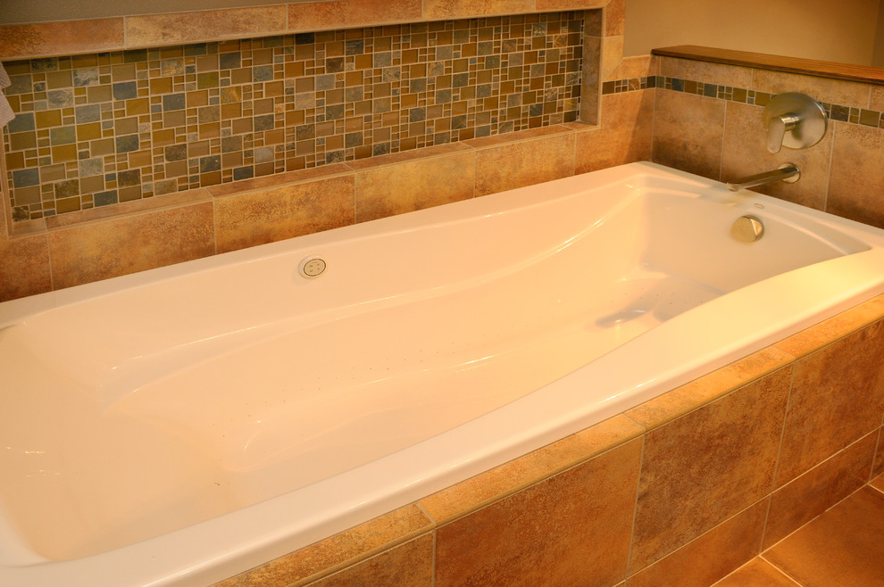 Immagine di una stanza da bagno chic con vasca da incasso e piastrelle beige