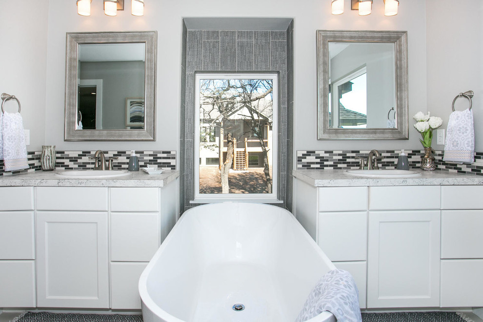 Exempel på ett mellanstort modernt en-suite badrum, med vita skåp, ett fristående badkar, en toalettstol med hel cisternkåpa, flerfärgad kakel, keramikplattor, grå väggar, klinkergolv i keramik, laminatbänkskiva och grått golv