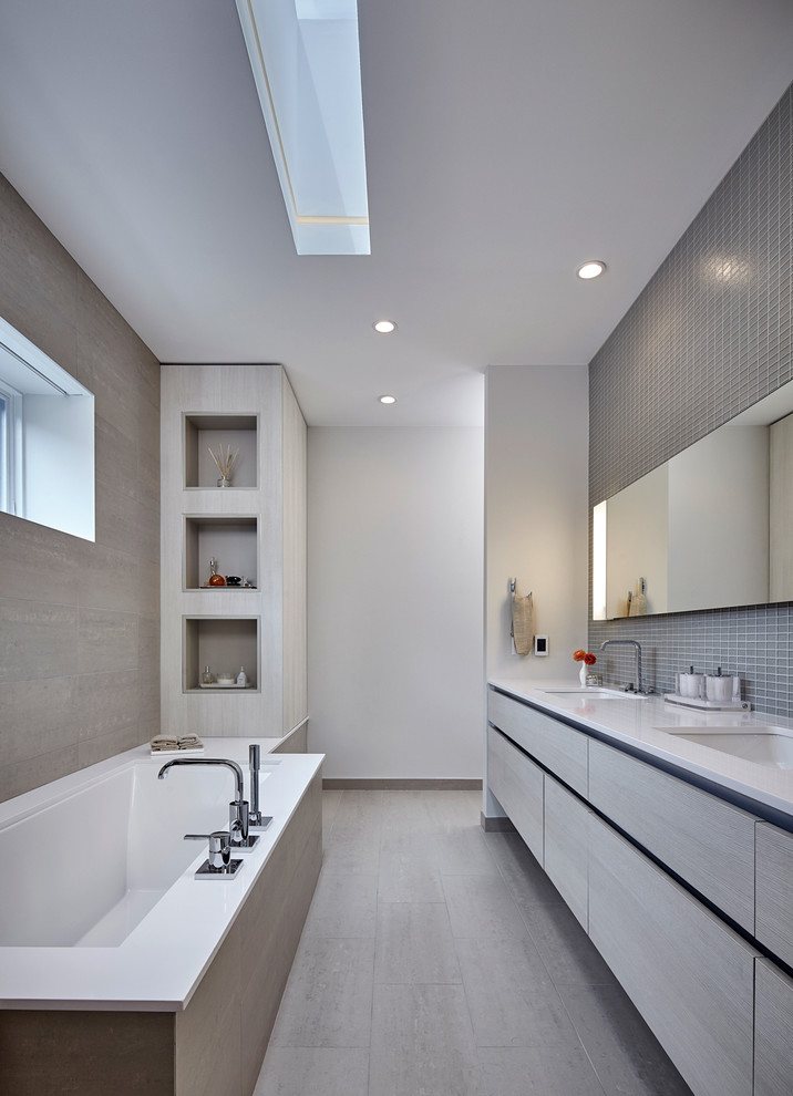 Photo of a large contemporary bathroom in Chicago with flat-panel cabinets, grey cabinets, a submerged bath, grey tiles, mosaic tiles, white walls and a submerged sink.