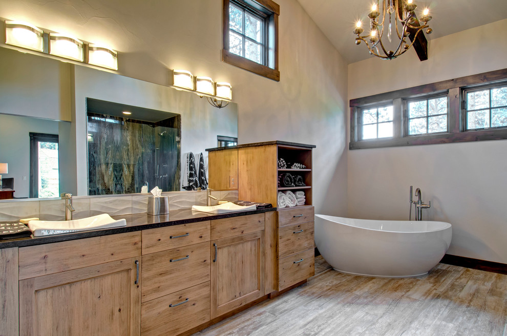 This is an example of a rustic bathroom in Denver with a built-in sink, recessed-panel cabinets, medium wood cabinets, a freestanding bath, grey walls and medium hardwood flooring.