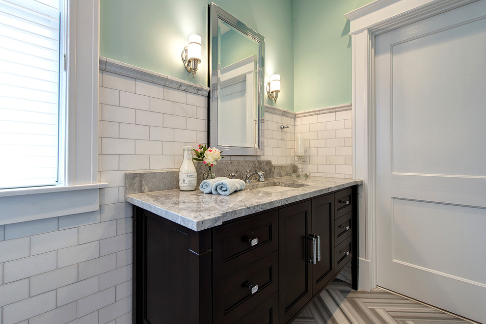 Bild på ett stort vintage grå grått en-suite badrum, med ett undermonterad handfat, ett fristående badkar, en hörndusch, vit kakel, blå väggar, grått golv, dusch med gångjärnsdörr, marmorkakel, marmorgolv, skåp i mellenmörkt trä, en toalettstol med separat cisternkåpa, marmorbänkskiva och luckor med infälld panel