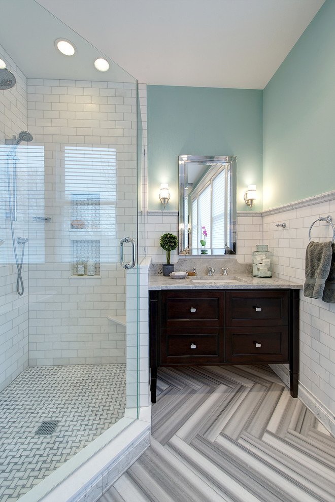 Réalisation d'une grande salle de bain principale design en bois brun avec une baignoire indépendante, une douche d'angle, un carrelage blanc, un mur bleu, un lavabo encastré, un sol gris, une cabine de douche à porte battante, du carrelage en marbre, un sol en marbre, un placard en trompe-l'oeil, WC séparés, un plan de toilette en marbre et un plan de toilette gris.