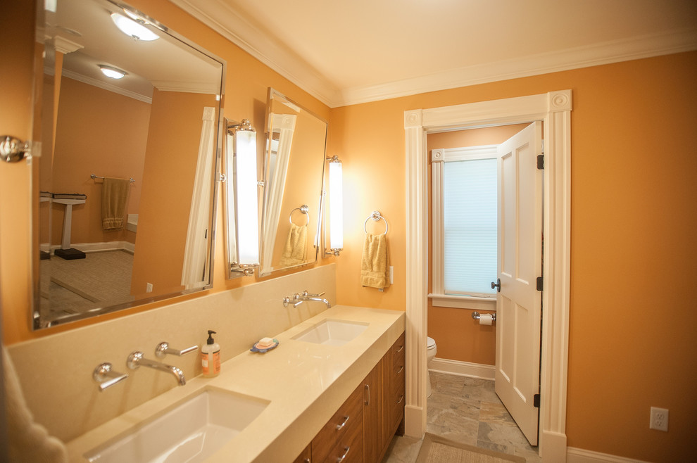 Inredning av ett klassiskt stort en-suite badrum, med släta luckor, skåp i mellenmörkt trä, ett badkar i en alkov, en dusch i en alkov, en toalettstol med hel cisternkåpa, grå kakel, stenhäll, orange väggar, skiffergolv, ett undermonterad handfat och bänkskiva i kvartsit