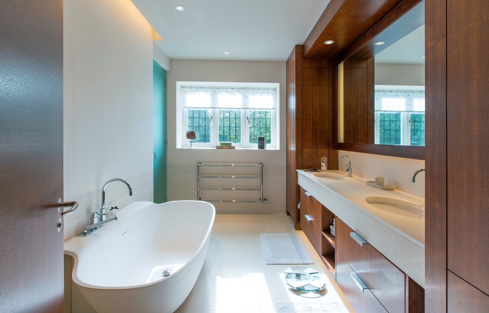 Réalisation d'une salle de bain principale design en bois brun avec un lavabo encastré, un placard à porte plane, une baignoire indépendante, un carrelage beige et un mur blanc.