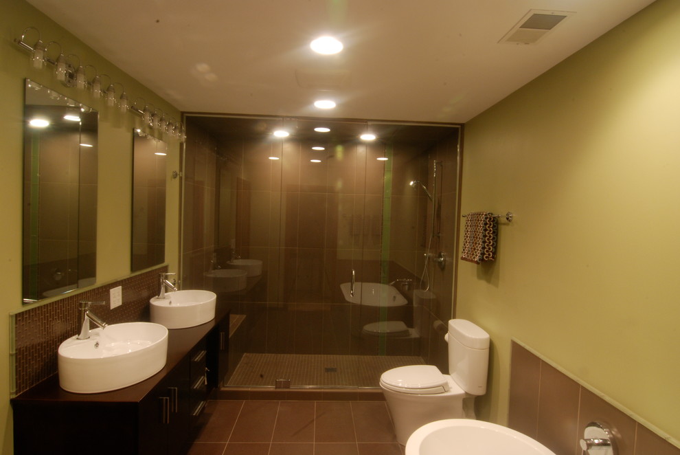 Свежая идея для дизайна: большая главная ванная комната в современном стиле с настольной раковиной, плоскими фасадами, коричневыми фасадами, столешницей из дерева, отдельно стоящей ванной, душем в нише, раздельным унитазом, зеленой плиткой, стеклянной плиткой, зелеными стенами и полом из керамогранита - отличное фото интерьера