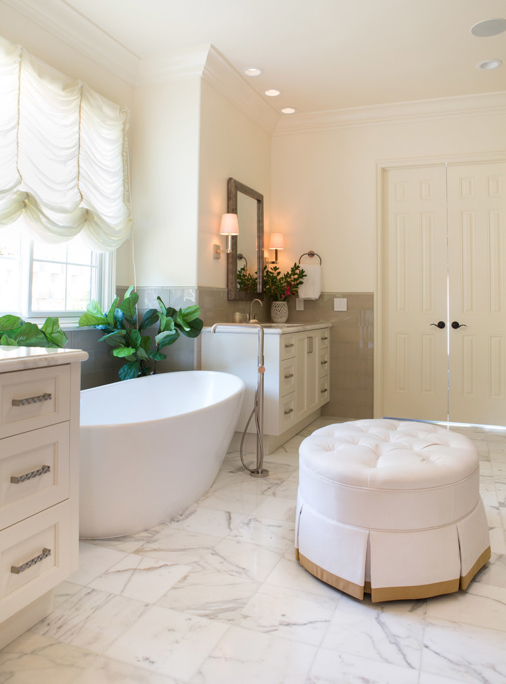 Идея дизайна: большая главная ванная комната в классическом стиле с фасадами в стиле шейкер, белыми фасадами, отдельно стоящей ванной, угловым душем, унитазом-моноблоком, белой плиткой, стеклянной плиткой, белыми стенами, мраморным полом, врезной раковиной и мраморной столешницей