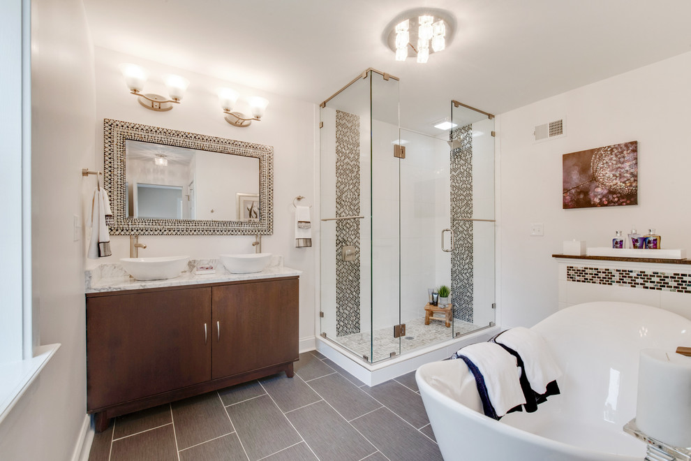 Стильный дизайн: большая главная ванная комната в стиле неоклассика (современная классика) с плоскими фасадами, темными деревянными фасадами, отдельно стоящей ванной, угловым душем, раздельным унитазом, белой плиткой, керамической плиткой, белыми стенами, полом из керамической плитки, настольной раковиной, мраморной столешницей, серым полом, душем с распашными дверями, серой столешницей, тумбой под две раковины и напольной тумбой - последний тренд