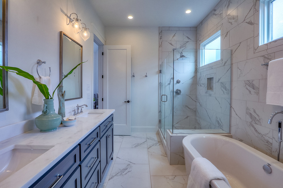 Design ideas for a large traditional ensuite bathroom in Nashville with flat-panel cabinets, blue cabinets, a freestanding bath, a corner shower, white tiles, marble tiles, white walls, marble flooring, a submerged sink, engineered stone worktops, white floors, a hinged door and white worktops.