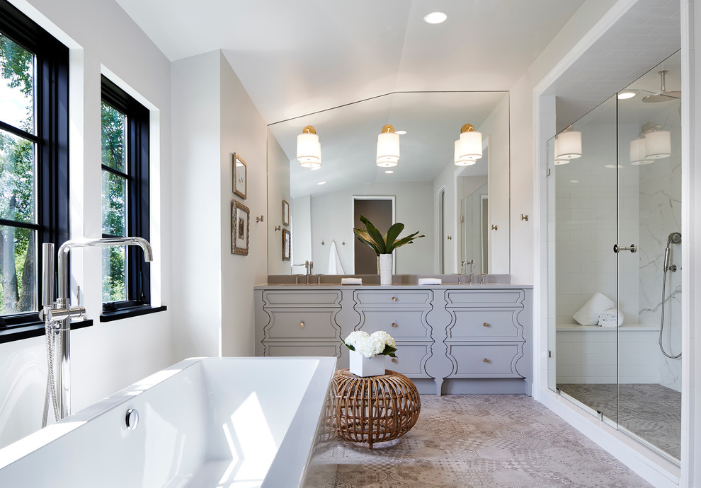 Diseño de cuarto de baño principal clásico renovado de tamaño medio con puertas de armario grises, bañera exenta, ducha empotrada, ducha con puerta con bisagras, lavabo bajoencimera, sanitario de dos piezas, baldosas y/o azulejos blancos, baldosas y/o azulejos de mármol, paredes blancas, suelo de azulejos de cemento, encimera de cuarcita, suelo beige y armarios con paneles empotrados