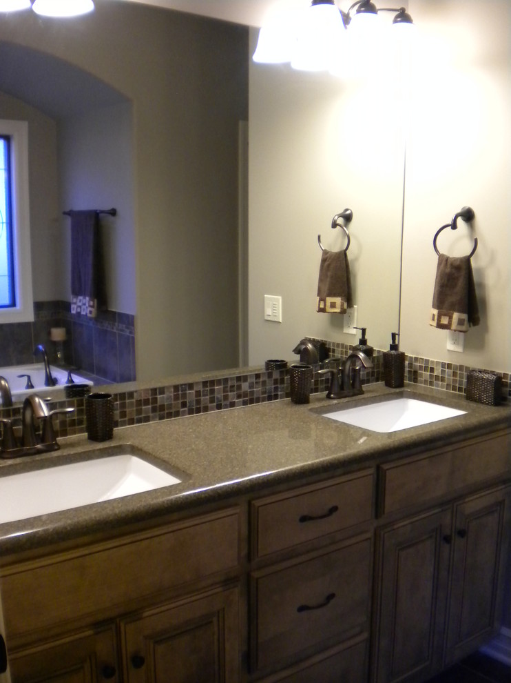 Foto på ett vintage en-suite badrum, med ett undermonterad handfat, luckor med upphöjd panel, skåp i mellenmörkt trä, bänkskiva i kvarts, ett badkar i en alkov, flerfärgad kakel och klinkergolv i porslin
