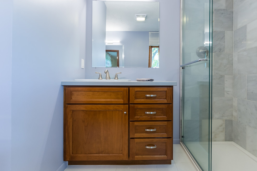 Photo of a medium sized midcentury ensuite bathroom in Omaha with white floors, beaded cabinets, medium wood cabinets, an alcove shower, a two-piece toilet, grey tiles, marble tiles, purple walls, porcelain flooring, a built-in sink, laminate worktops, a sliding door and grey worktops.