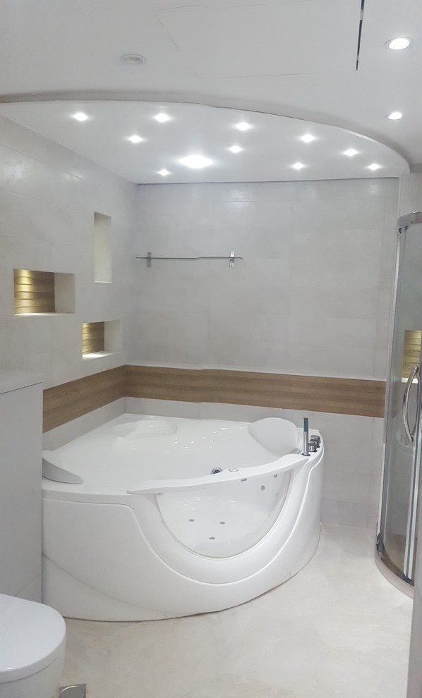 Пример оригинального дизайна: большая главная ванная комната в стиле модернизм с плоскими фасадами, серыми фасадами, гидромассажной ванной, угловым душем, инсталляцией, серой плиткой, каменной плиткой, серыми стенами, врезной раковиной и мраморной столешницей