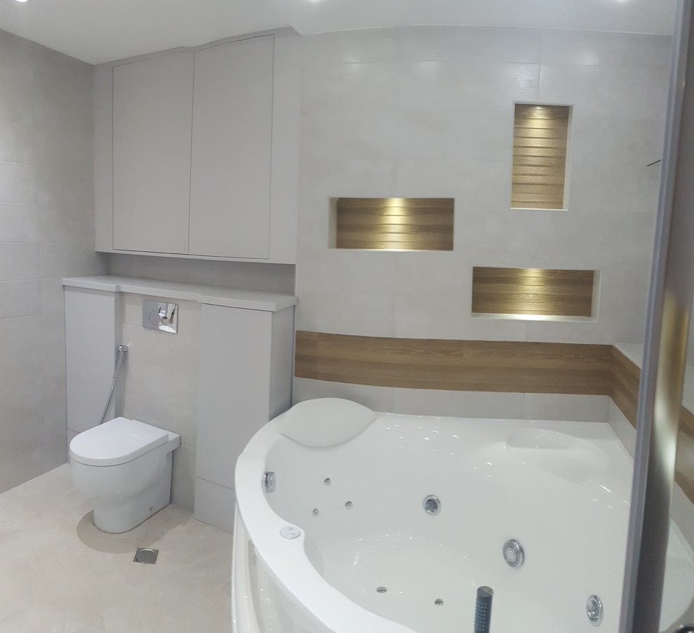 Inredning av ett modernt stort en-suite badrum, med släta luckor, grå skåp, en jacuzzi, en hörndusch, en vägghängd toalettstol, grå kakel, stenkakel, grå väggar, ett undermonterad handfat och marmorbänkskiva