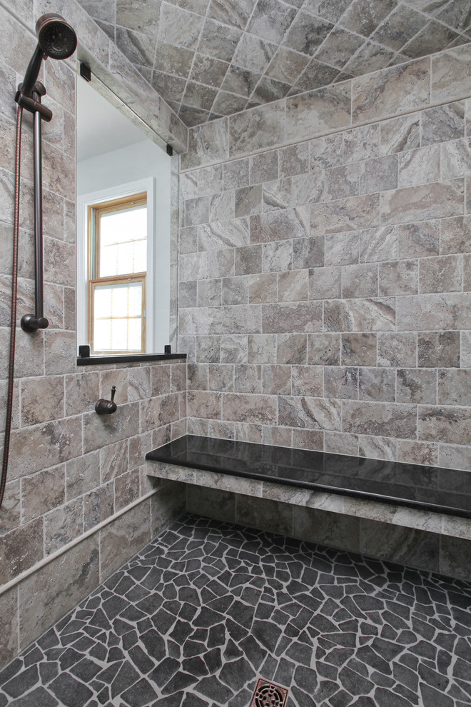 Exemple d'une grande douche en alcôve principale chic avec un placard à porte shaker, des portes de placard noires, une baignoire posée, un carrelage de pierre, un sol en carrelage de céramique, un lavabo encastré et un plan de toilette en surface solide.