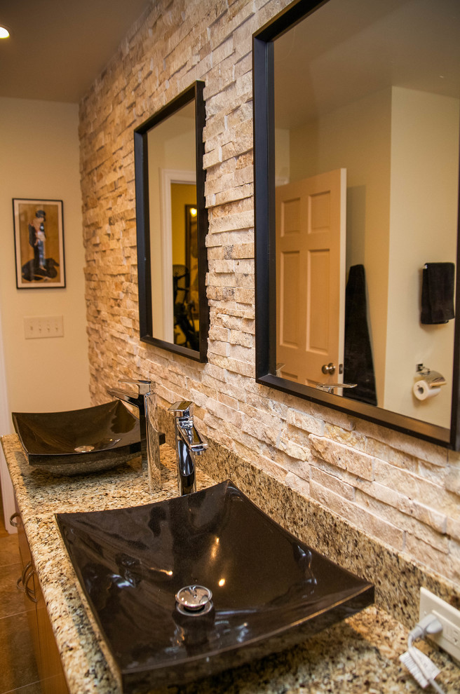 Asiatisk inredning av ett mellanstort en-suite badrum, med ett fristående handfat, skåp i mellenmörkt trä, granitbänkskiva, ett badkar i en alkov, en dusch/badkar-kombination, en toalettstol med hel cisternkåpa, beige kakel, stenhäll, beige väggar och travertin golv